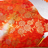 Detail of red kimono pillow showing woven gold flower design and crane head.