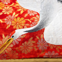 Flying crane pillow detail, white crane over red silk with woven gold flowers.