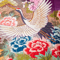 Detail of wedding kimono crane pillow flying over multicoloured flowers.